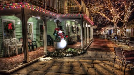 Mental Health durinng Holidays. Cozy Christmas Village with a snowman on the porch while it is dark.